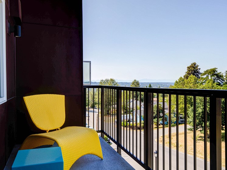 Private Patio Overlooking Parking Lot with Yellow Chair, Gate and Trees